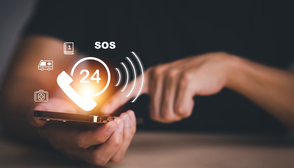 Person using smartphone with glowing 24/7 SOS emergency service icons above the screen.