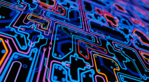 Colorful, glowing circuitry lines forming a complex electronic pattern on a dark background.