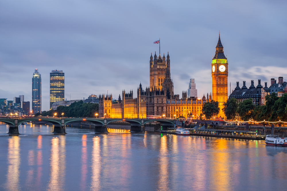 The Houses of Parliament and Big Ben in London, illuminated at dusk by the River Thames.
