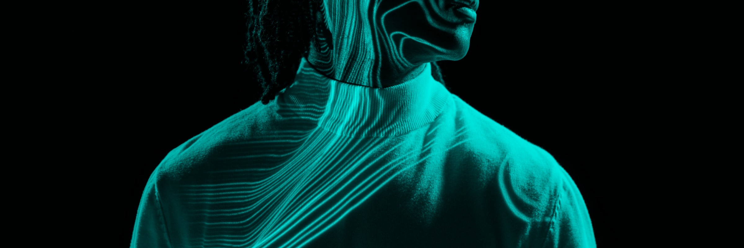 Silhouette of a person with glowing turquoise lines tracing patterns over their face and clothing on a black background.