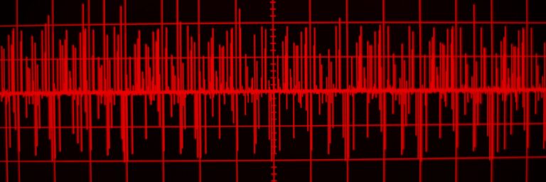 A red audio waveform displayed on a black background, resembling a sound or seismic signal on a screen.