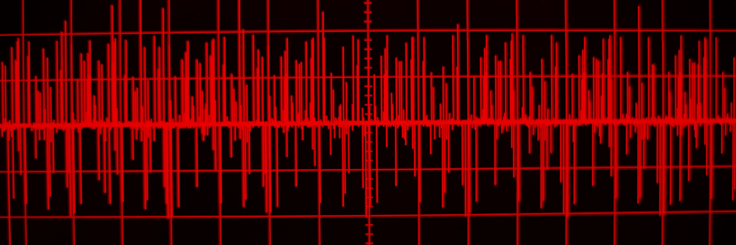 A red audio waveform displayed on a black background, resembling a sound or seismic signal on a screen.