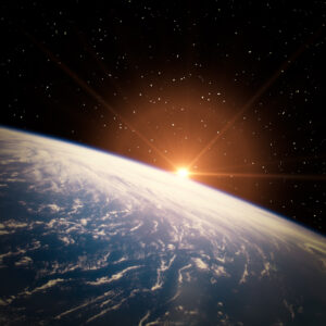 Sunrise over Earth’s horizon seen from space with a starry sky in the background.