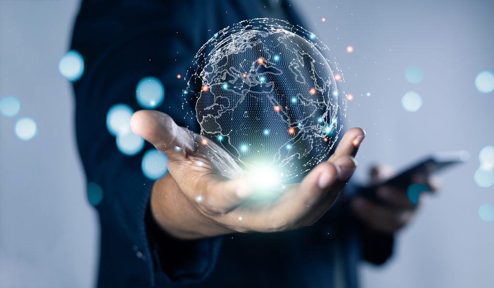 A person holds a glowing digital globe hologram, symbolizing global technology and connectivity.