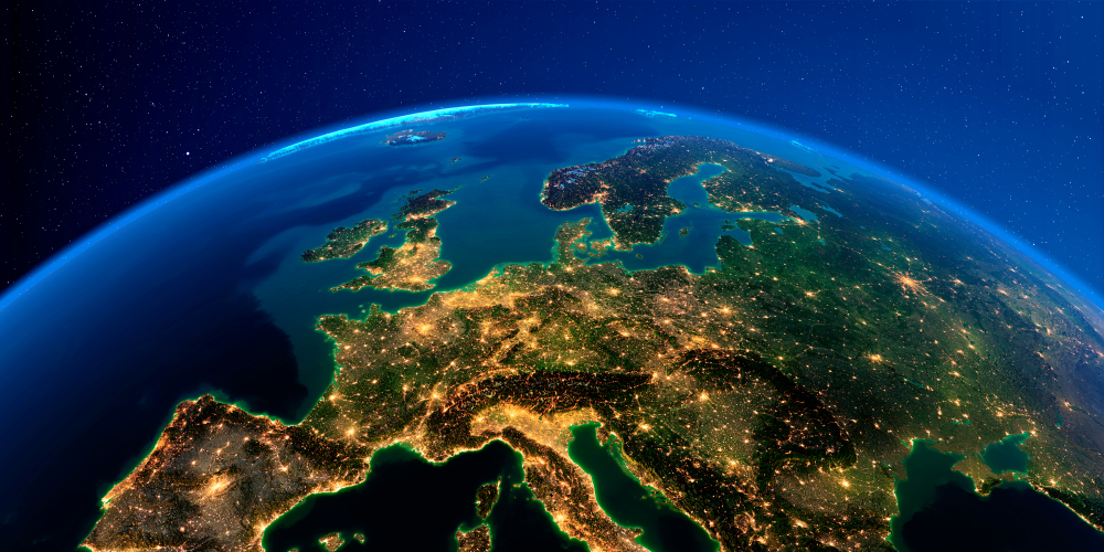 View of Europe from space at night, showing city lights and the curvature of the Earth against a starry sky.