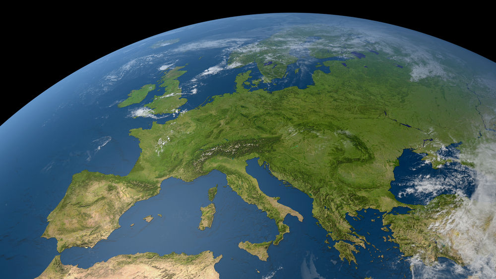 View of Europe from space, showing land, seas, and cloud cover under sunlight.