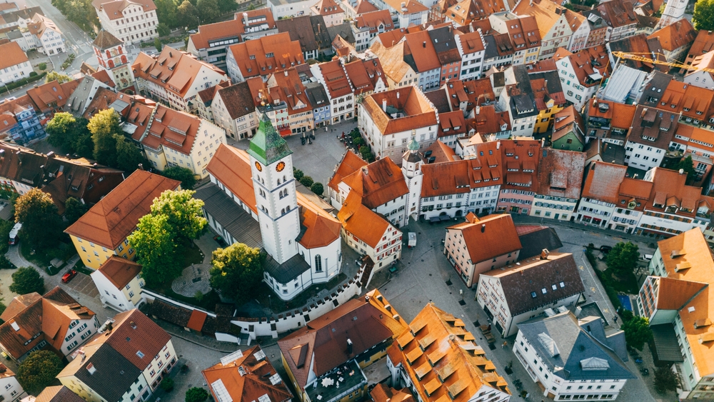 Aerial view of a European town with red-roofed buildings and a central white church.