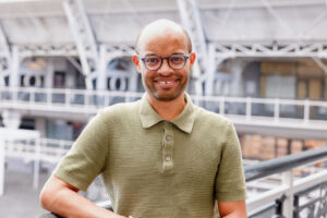 A smiling man in glasses and a green polo shirt.