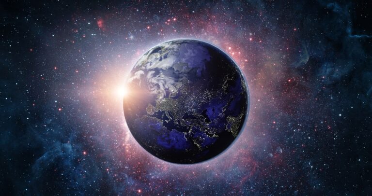 Earth viewed from space with city lights visible on the night side and a sunrise glowing on the horizon.